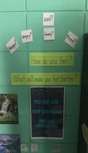 Wall in a classroom with a poster that reads "How do you feel? What will make you feel better?"