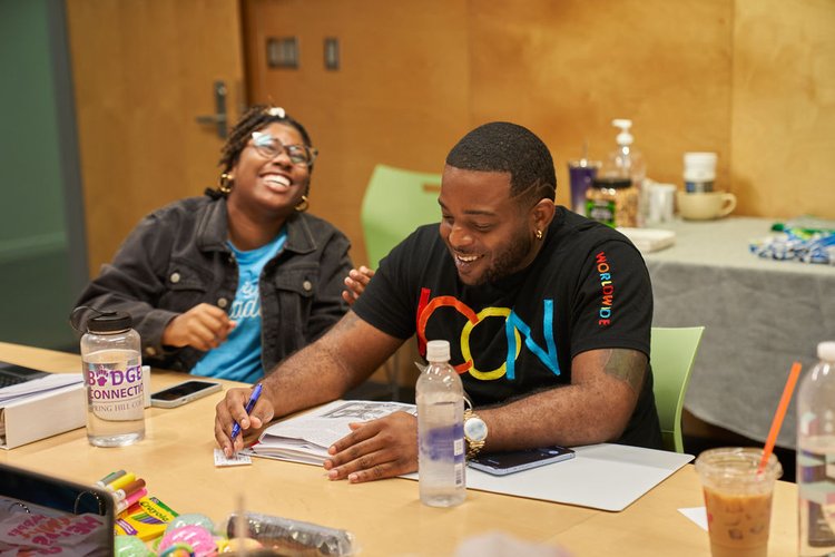 Two people smile at a table during a workshop
